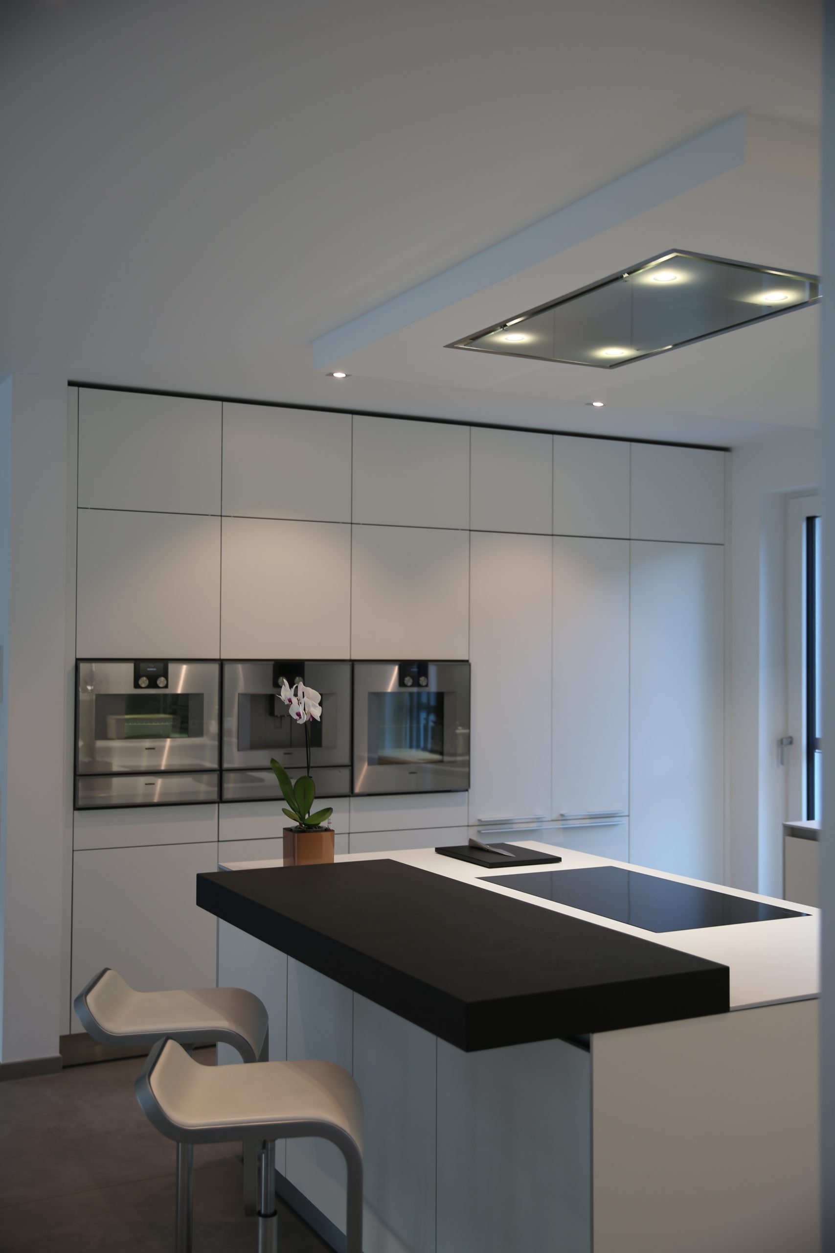 Kochinsel mit schwarzer Barplatte und Hockern – bulthaup b3 Designküche in Weiß